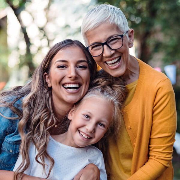 smiling family of young girl, adult woman, and mature woman