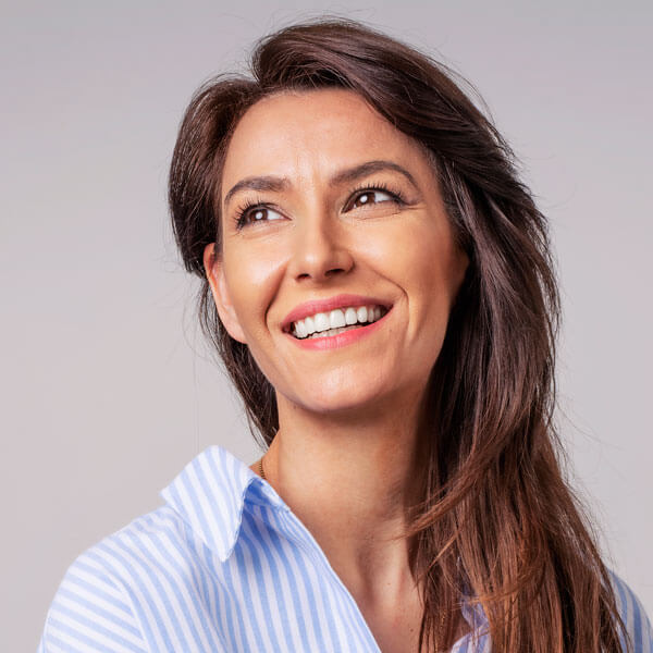 adult woman smiling against gray wall